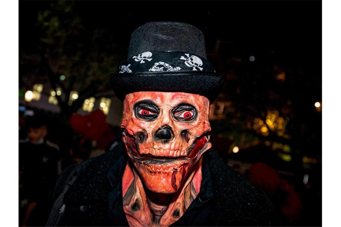 Ein Mann mit einer Totenkopf-Maske und glühenden roten Augen bei der Essener Halloween-Parade. Neben fantasievollen Kostümen gab es in der Nacht in Teilen Deutschlands auch Ruhestörungen, Böllerwürfe und Ausschreitungen. Foto: Malte Krudewig/dpa