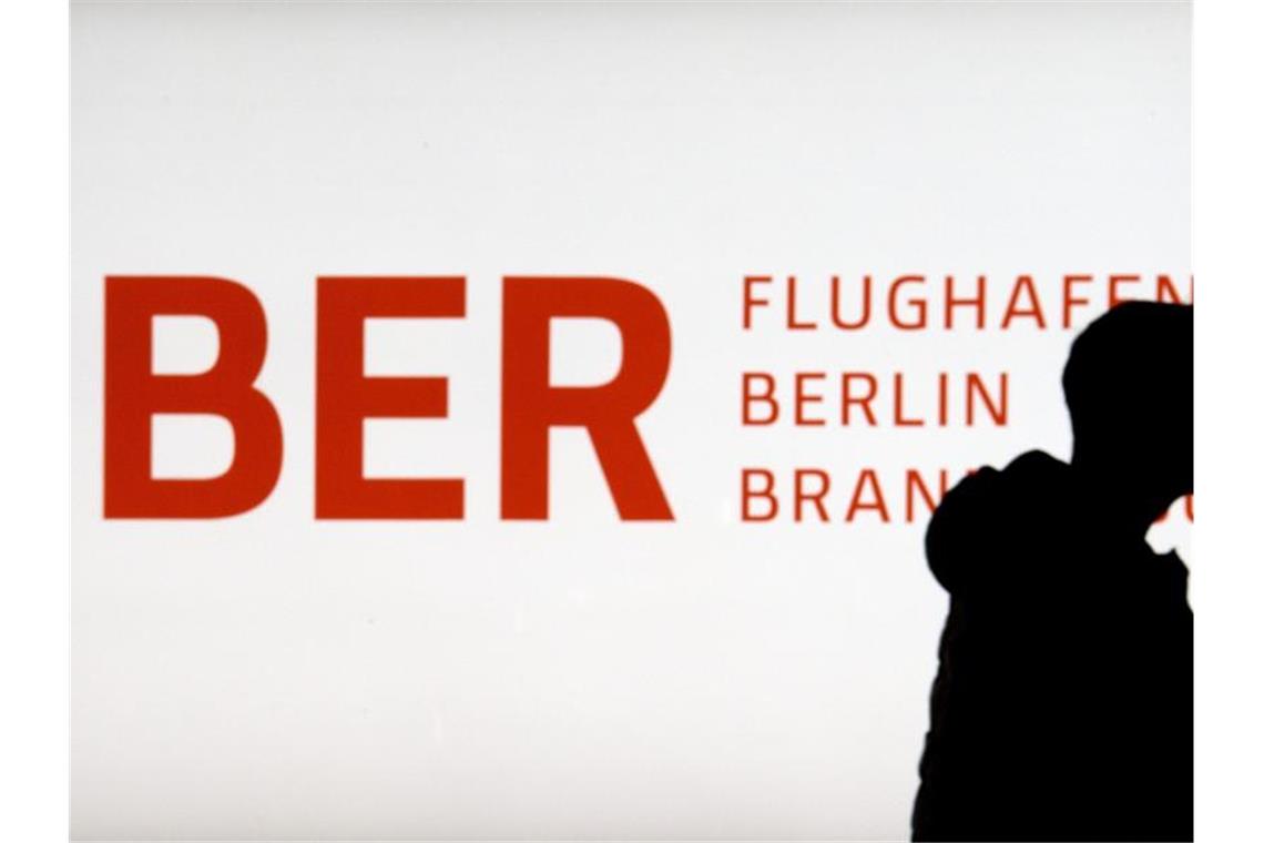 BER-Aufsichtsrat befasst sich mit Lütke-Daldrup-Nachfolge Ein Mann mit Mund-Nase-Maske geht im Terminal 1 des Flughafens Berlin Brandenburg Willy Brandt an dem erleuchteten Logo BER vorbei. Foto: Soeren Stache/dpa-Zentralbild/dpa