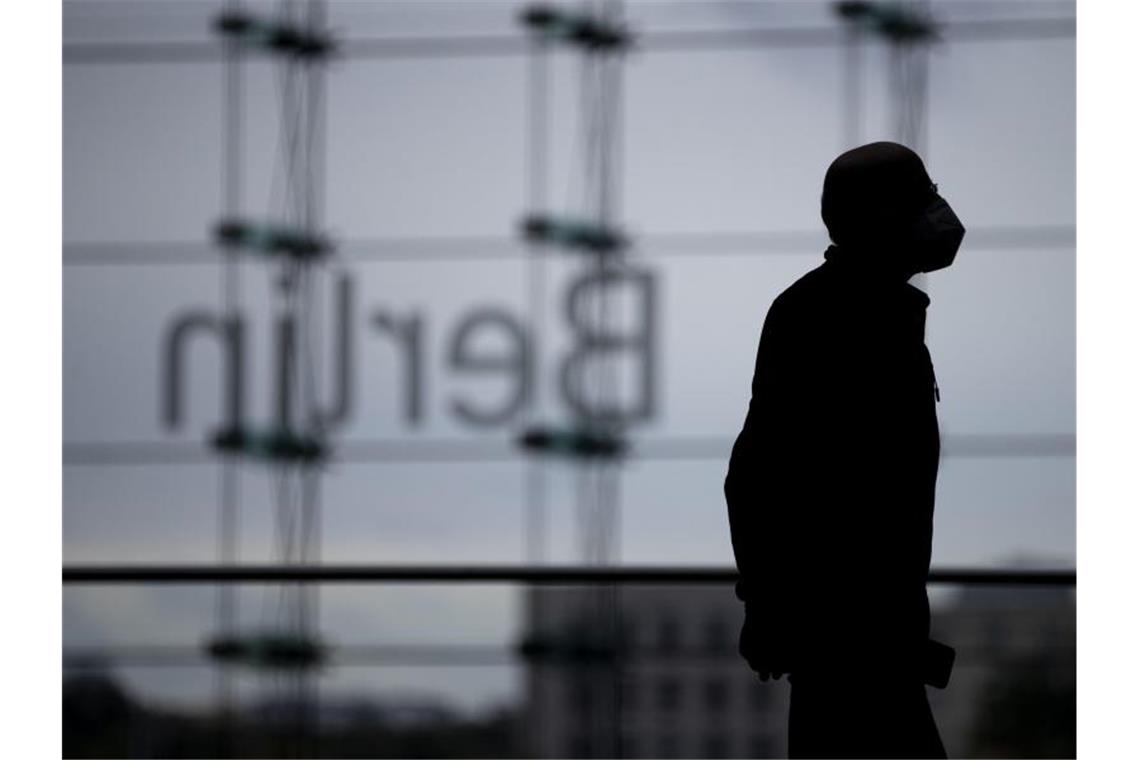 Gerät die Corona-Ausbreitung außer Kontrolle? Ein Mann mit Mund-Nasen-Schutz im Berliner Hauptbahnhof vor dem „Berlin“-Schriftzug. Foto: Christoph Soeder/dpa
