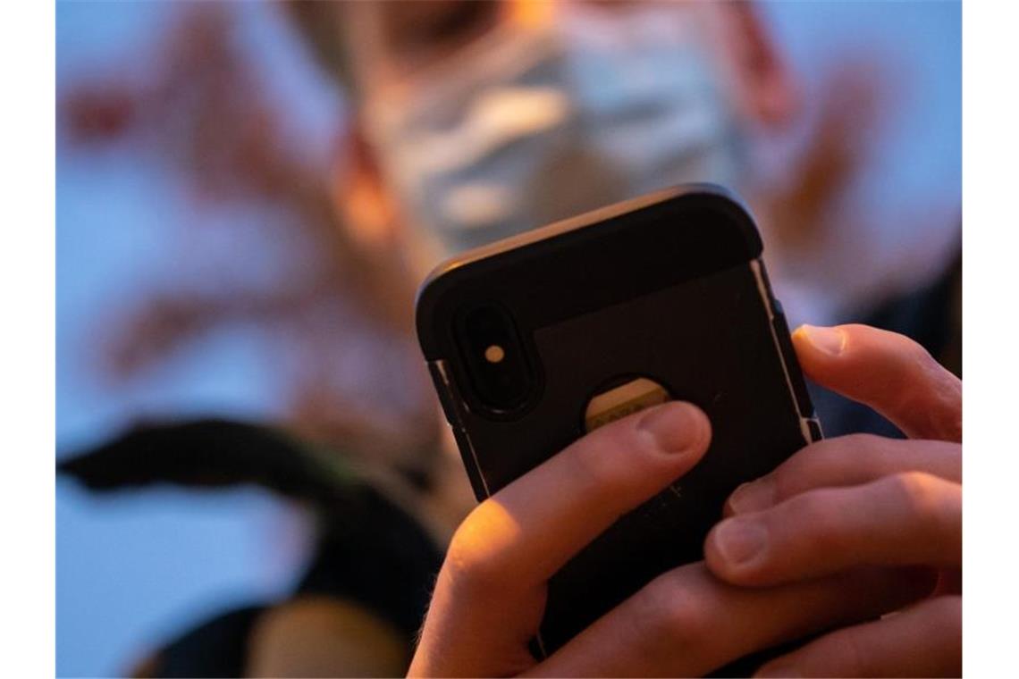 Ein Mann mit Mund- und Nasenmaske tippt auf seinem Smartphone. Foto: Sebastian Gollnow/dpa/Archiv