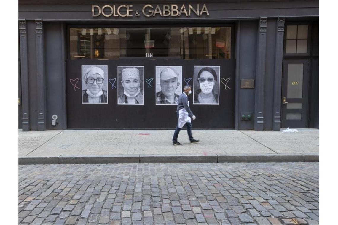 Ein Mann mit Mundschutz geht an einer geschlossenen Boutique in New York vorbei. Foto: Mary Altaffer/AP/dpa