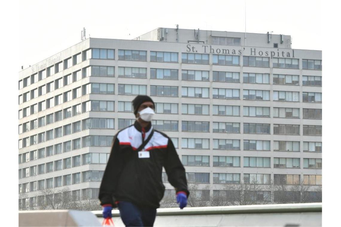 Ein Mann mit Mundschutz vor dem St. Thomas's Hospital in London. Johnson wurde hier nun auf eine normale Station verlegt. Foto: Dominic Lipinski/PA Wire/dpa