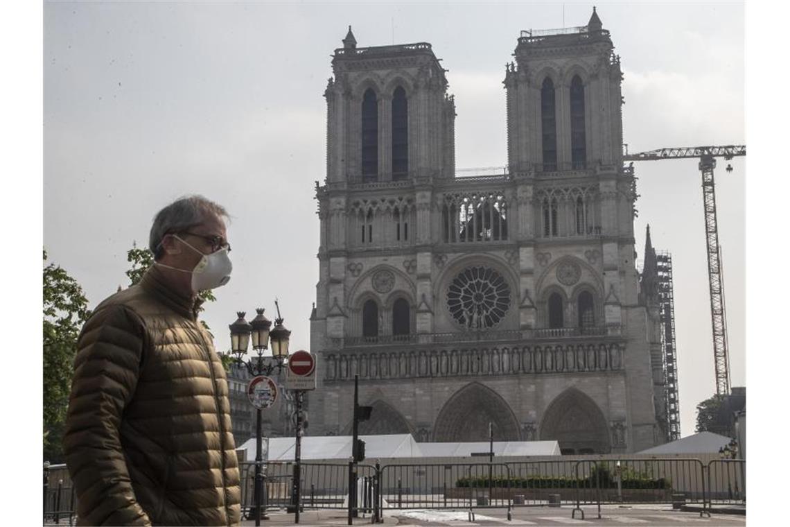 Ein Mann mit Mundschutz vor der Baustelle der Kathedrale Notre Dame in Paris. Foto: Michel Euler/AP/dpa