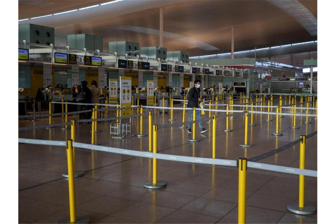 Ein Mann mit Mundschutzmaske im leeren Terminal eines Flughafens. Foto: Emilio Morenatti/AP/dpa