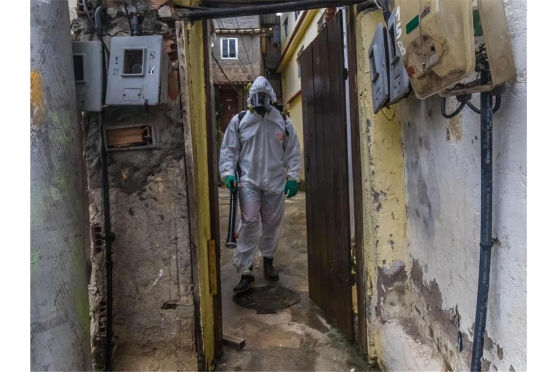 Ein Mann mit Schutzkleidung und einem Gerät zur Straßendesinfektion in einem Armenviertel von Rio de Janeiro. Foto: Ellan Lustosa/ZUMA Wire/dpa