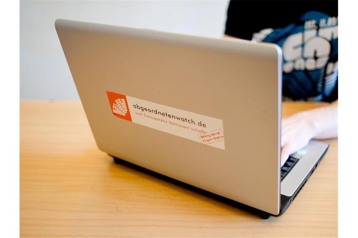 Ein Mann nutzt einen Laptop mit einem Aufkleber mit der Internetseite „abgeordnetenwatch.de“. Foto: picture alliance / dpa/Archivbild