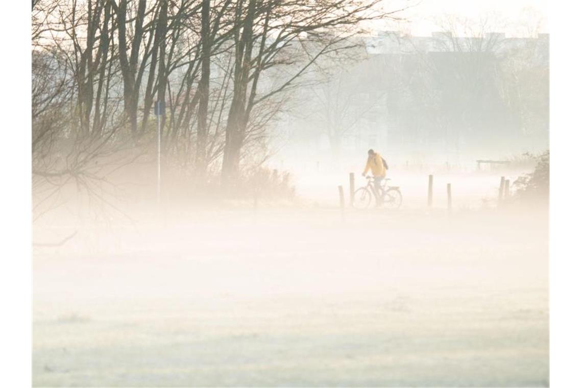 Ein Mann radelt durch den morgendlichen Nebel. Foto: Julian Stratenschulte/dpa/Archivbild