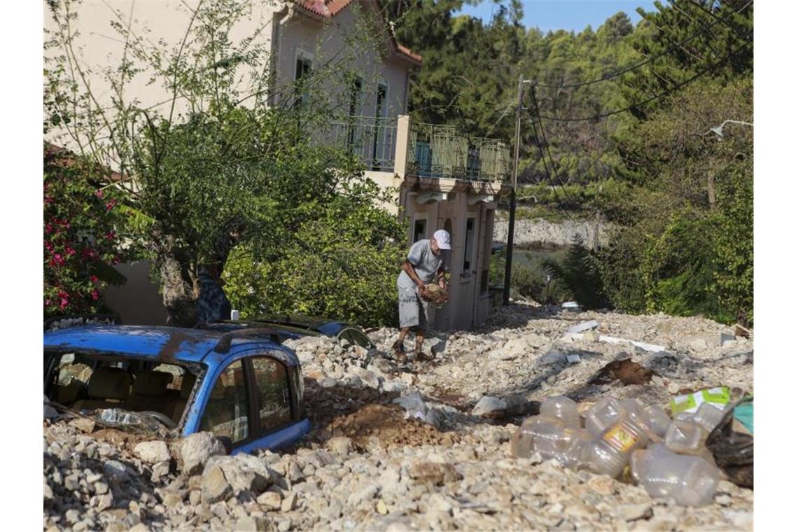 Ein Mann räumt Steine aus dem Weg. In zahlreichen Regionen Westgriechenlands und auf der Halbinsel Peloponnes fiel zudem der Strom aus. Foto: Nikiforos Stamenis/AP/dpa