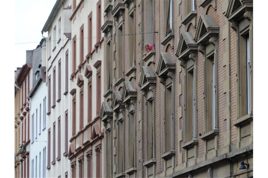 Ein Mann raucht am Fenster seiner Wohnung. Foto: Arne Dedert/dpa/Archivbild