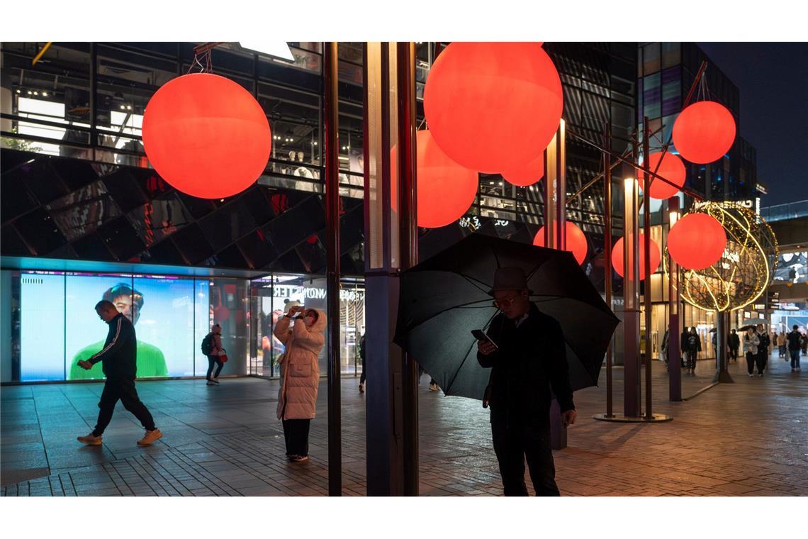 Bilde des Tages Ein Mann schaut auf sein Telefon in der Nähe von roten Zierkugeln am Taikoo Li Sanlitun Einkaufszentrum in Peking.