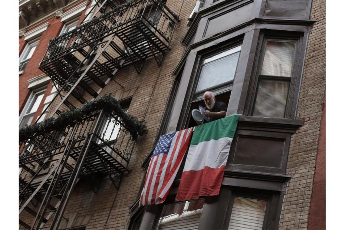Ein Mann schlägt im New Yorker Stadtteil Little Italy Topfdeckel gegeneinander, um seine Unterstützung für die Helfer gegen die Pandemie zu zeigen. Foto: Mark Lennihan/AP/dpa