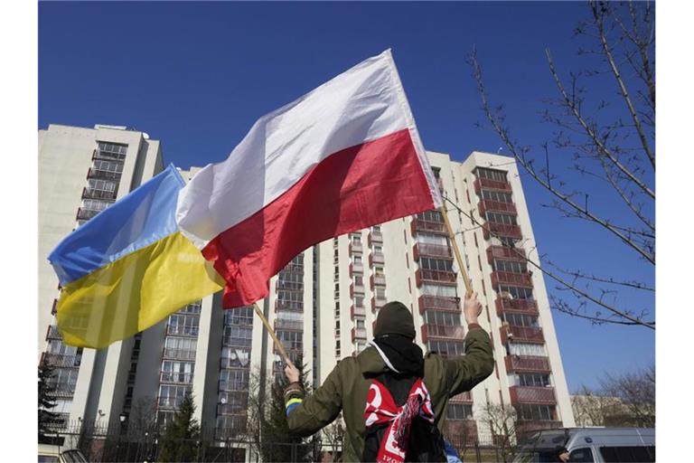 Ein Mann schwenkt während einer Demonstration in Warschau die ukrainische und die polnische Flagge vor einem Gebäude, in dem russische Diplomaten untergebracht sind. Foto: Czarek Sokolowski/AP/dpa