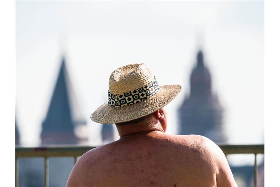 Hitze in Deutschland bringt möglicherweise Temperaturrekord Ein Mann sitzt bei am Rheinufer mit Blick auf den Mainzer Dom und schützt sich mit einem Hut gegen die Sonne. Foto: Andreas Arnold