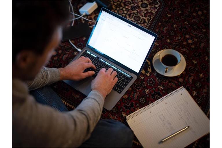Ein Mann sitzt im Homeoffice mit Laptop auf dem Teppich und arbeitet. (Archivbild). Foto: Sina Schuldt/dpa