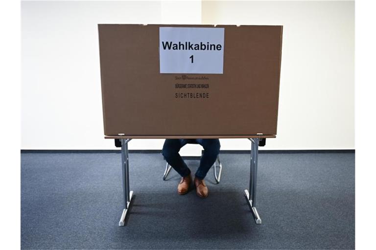 Ein Mann sitzt im Wahlraum des Briefwahllokals Frankfurt Innenstadt hinter einer Wahlkabine. Foto: Arne Dedert/dpa