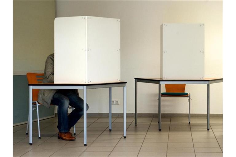 Ein Mann sitzt in einer Wahlkabine. Foto: Peter Endig/dpa-Zentralbild/Archiv