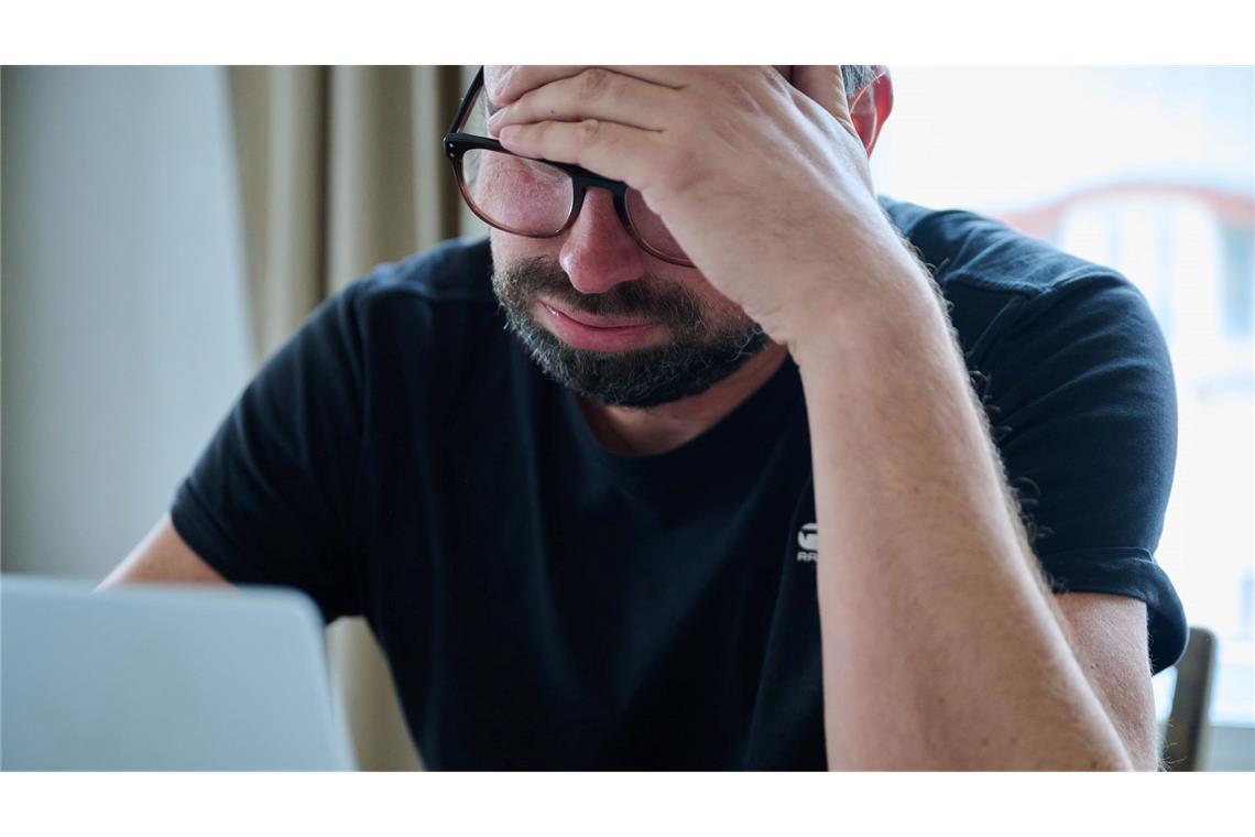 Warum tiefe Seufzer Menschen guttun Ein Mann sitzt vor einem Laptop und seufzt.