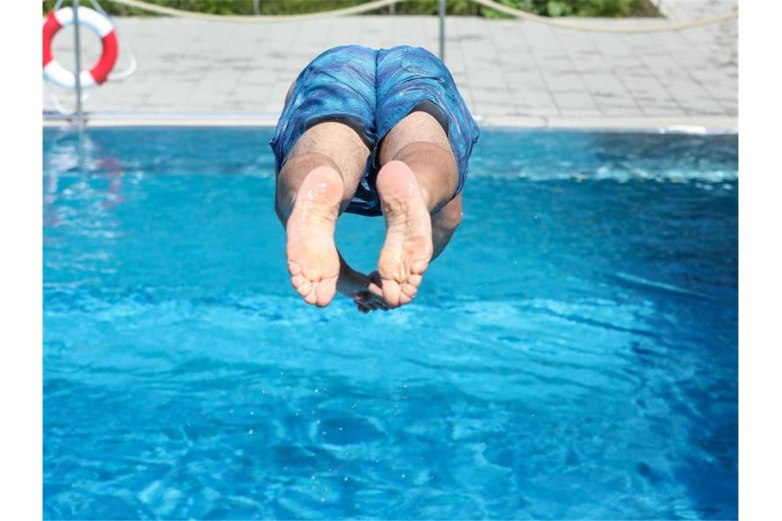 Ein Mann springt von einem Sprungbrett kopfüber ins Wasser. Foto: Thomas Warnack/dpa