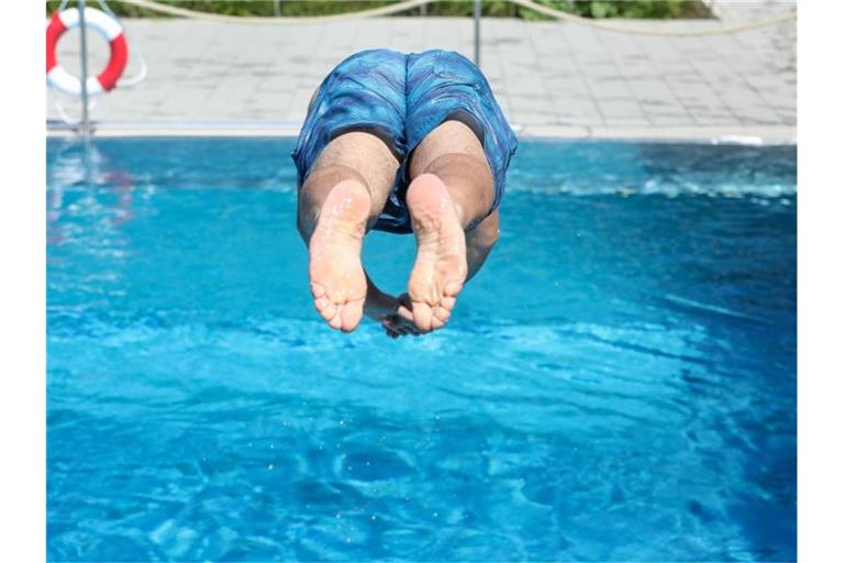 Ein Mann springt von einem Sprungbrett kopfüber ins Wasser. Foto: Thomas Warnack/dpa