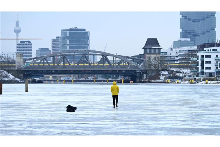 Ein Mann steht am Treptower Park in Berlin auf der zugefrorenen Spree.