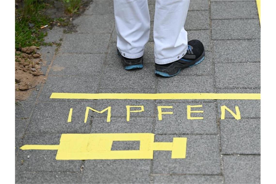 Polizeigewerkschaft gegen Impfpflicht Ein Mann steht an einem Covid-19-Impfcenter hinter der Bodenaufschrift "Impfen". Foto: Arne Dedert/dpa/POOL/dpa/Symbolbild