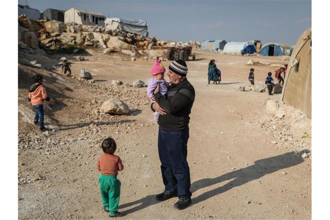 Ein Mann steht mit seinen Kindern in einem Flüchtlingslager in der Provinz Idlib. Foto: Anas Alkahrboutli/dpa/dpa