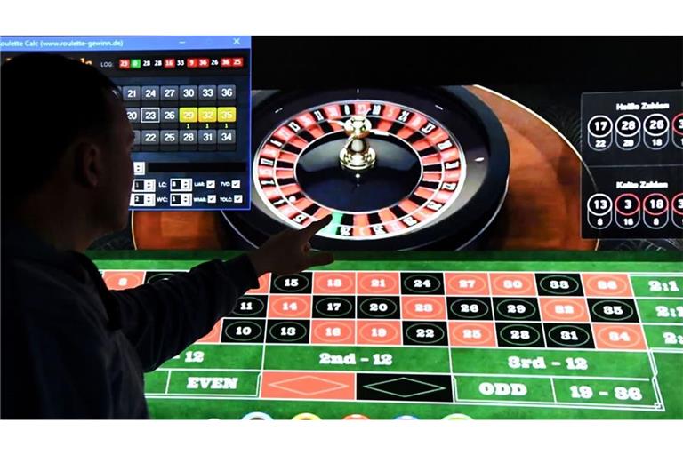 Ein Mann steht vor einem Bildschirm mit einer Seite für Online-Roulette. Um viel Geld auf Schwarz oder Rot zu setzen, muss man mittlerweile nicht mehr in ein Kasino oder eine Spielbank gehen.
