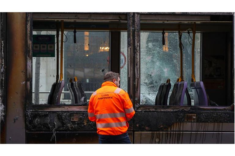 Ein Mann steht vor einer ausgebrannten Stadtbahn.
