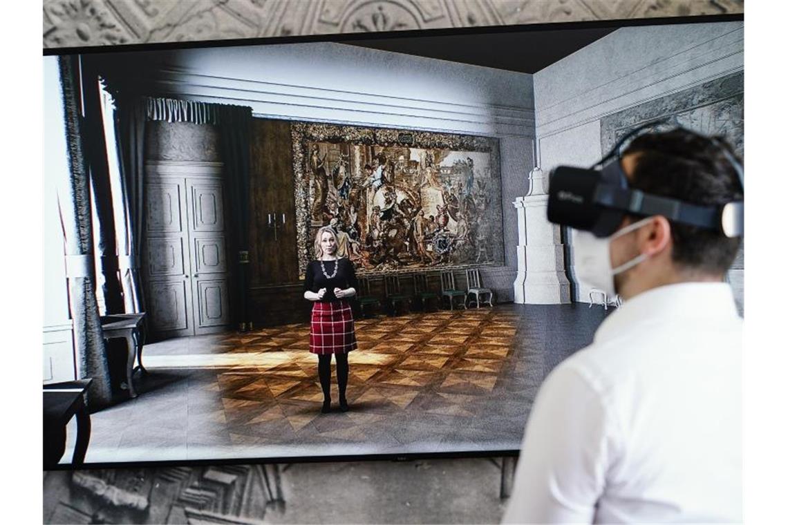 Ein Mann steht vor einer virtuellen Rekonstruktion von Räumen des Barockschlosses. Foto: Uwe Anspach/dpa