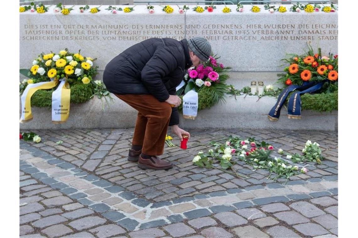 Ein Mann stellt an einer Gedenkstätte auf dem Altmarkt ein Grablicht auf. Foto: Jens Büttner/dpa-Zentralbild/dpa