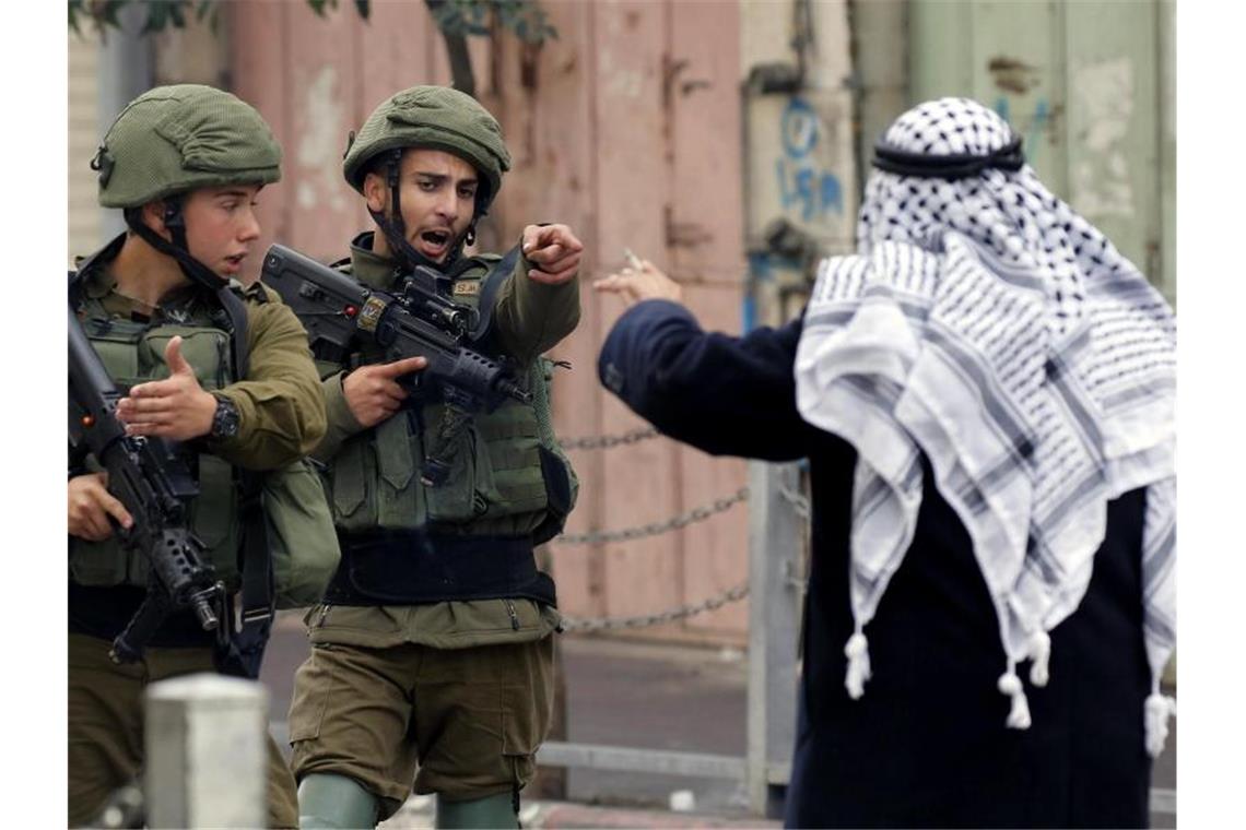 Ein Mann streitet in Hebron im Westjordanland mit israelischen Soldaten. Foto: Wisam Hashlamoun/Zuma Press/dpa/Archiv