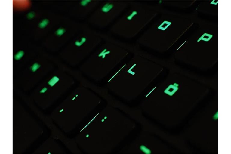 Ein Mann tippt auf einer beleuchteten Tastatur an einem Laptop. Foto: picture alliance / Nicolas Armer/dpa