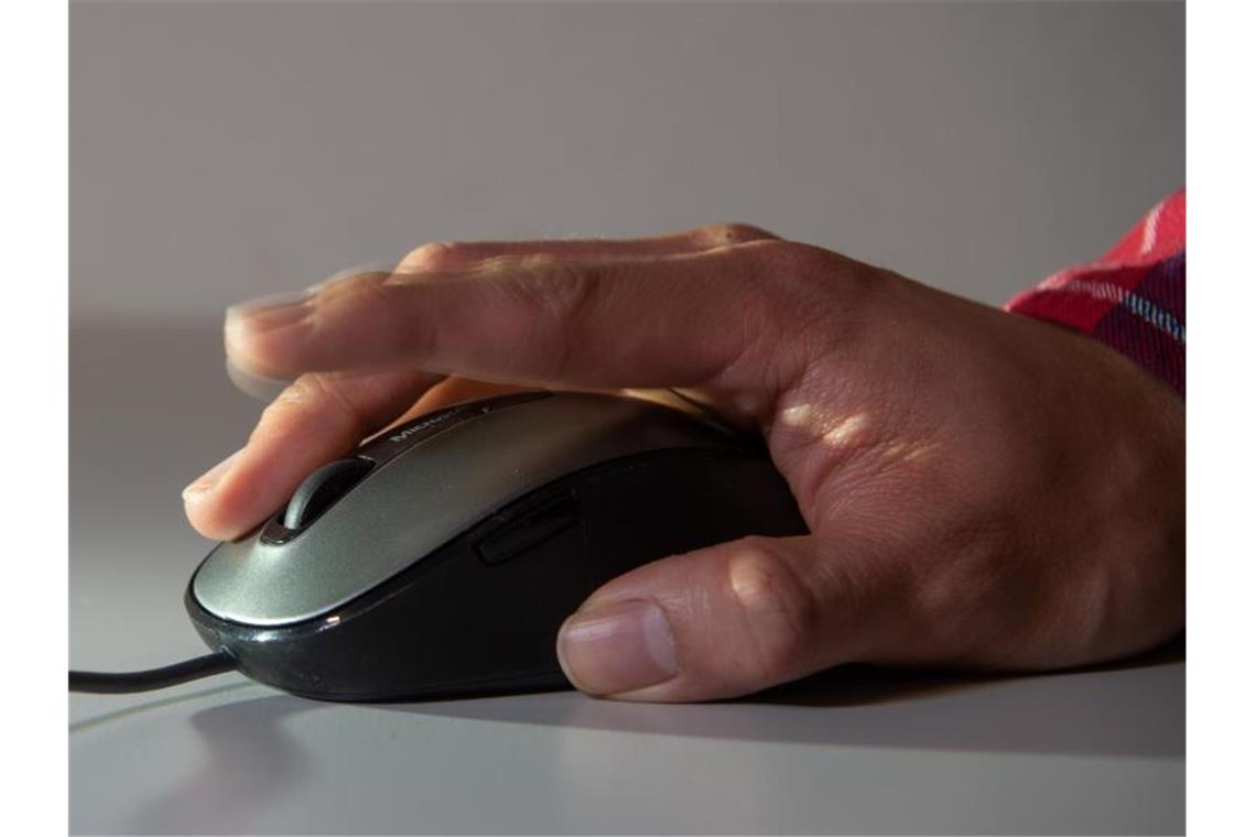 Ein Mann tippt die Linke Taste seiner Computermaus an. Foto: Christophe Gateau/dpa/Symbolbild