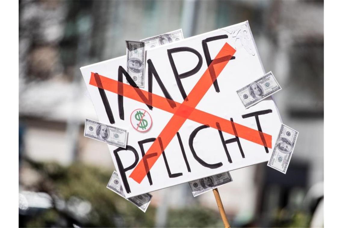 Verband: Angriffe auf Journalisten bei „Querdenker“-Demo Ein Mann trägt auf einer Demonstration der Initiative „Querdenken“ ein Schild mit einem durchgestrichenen „Impflicht“-Schriftzug. Foto: Christoph Schmidt/dpa/Symbolbild