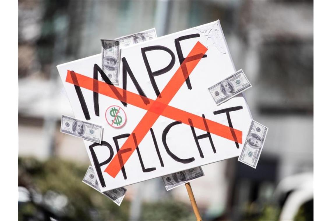 Verfassungsschutz: Impfpflicht radikalisiert „Querdenker“ Ein Mann trägt auf einer Demonstration ein Schild mit einem durchgestrichenen „Impflicht“-Schriftzug. Foto: Christoph Schmidt/dpa/Archivbild