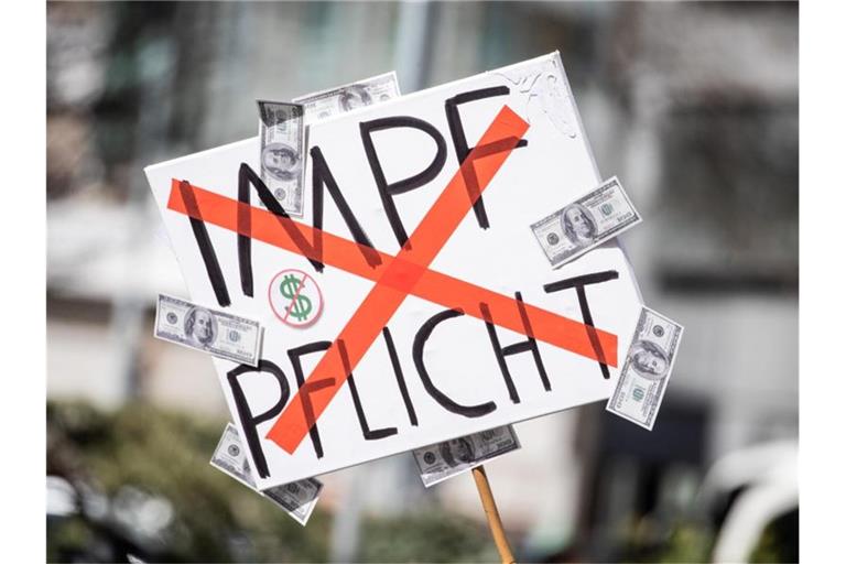 Ein Mann trägt auf einer Demonstration ein Schild mit einem durchgestrichenen „Impflicht“-Schriftzug. Foto: Christoph Schmidt/dpa/Archivbild