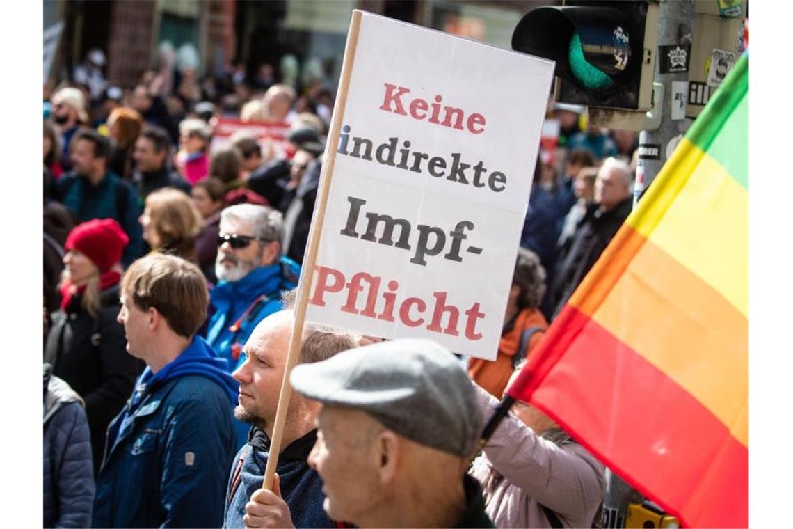 Ein Mann trägt ein Schild mit der Aufschrift „Keine indirekte Impf-Pflicht“. Foto: Christoph Schmidt/dpa/Archiv