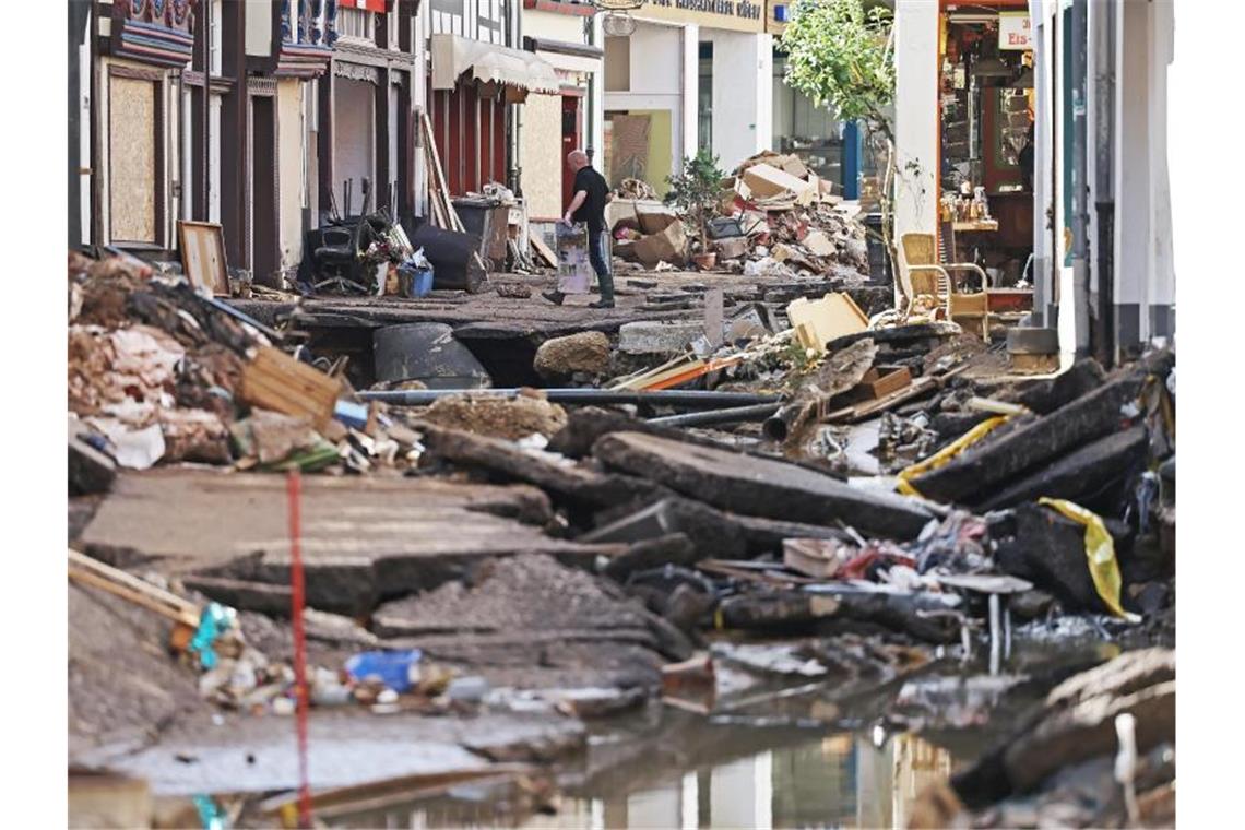 Laschet will Sondersitzung des Bundestags zu Fluthilfen Ein Mann trägt Trümmer aus einem Haus in Bad Münstereifel (Nordrhein-Westfalen). Foto: Oliver Berg/dpa