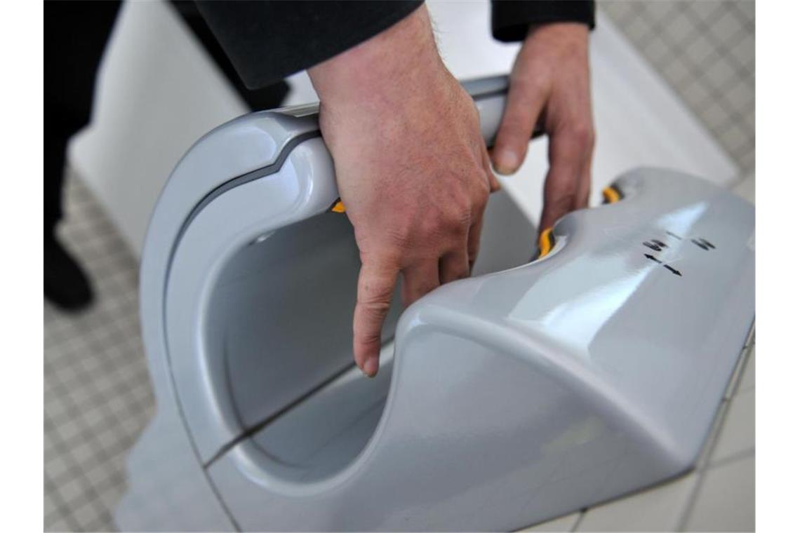 Corona: Händetrockner-Firmen beklagen Wettbewerbsverzerrung Ein Mann trocknet sich die Hände an einem elektrischen Händetrockner. Foto: picture alliance / dpa/Archivbild