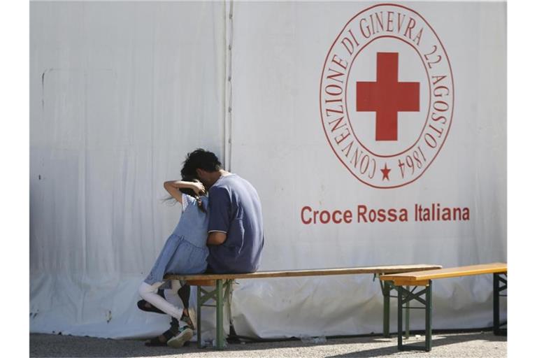 Ein Mann und ein Kind sitzen in einem Einsatzzentrum des italienischen Roten Kreuzes, Croce Rossa Italiana (CRI). Dort werden mit Hilfe der Armee und des Zivilschutzes afghanische Geflüchtete aufgenommen. Foto: Cecilia Fabiano/LaPresse via ZUMA Press/dpa