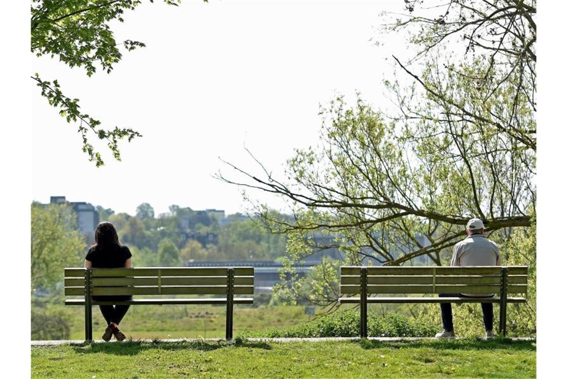 Fläche der Grünanlagen hat zugenommen Ein Mann und eine Frau sitzen mit dem größtmöglichen Abstand auf zwei Parkbänken. Foto: Caroline Seidel/dpa/Archivbild