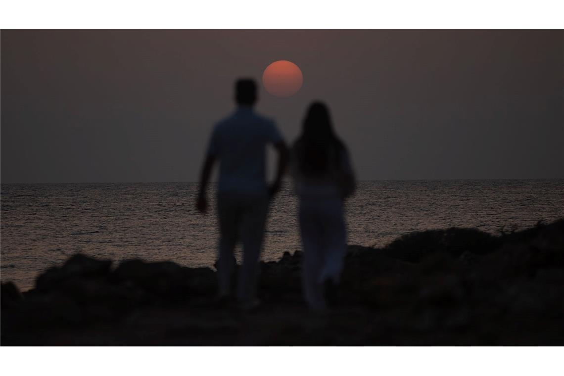 Ein Mann und eine Frau spazieren in der Nähe des Strandes Es Cargol in Santanyi auf Mallorca während des Sonnenuntergangs.