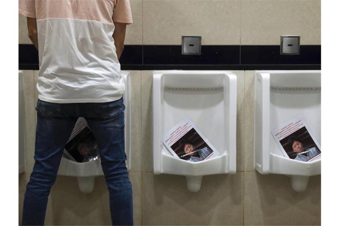 Ein Mann uriniert während einer Demonstration am Flughafen in einer Toilette auf Fotos von Carrie Lam, Regierungschefin von Hongkong. Foto: Vincent Yu/AP