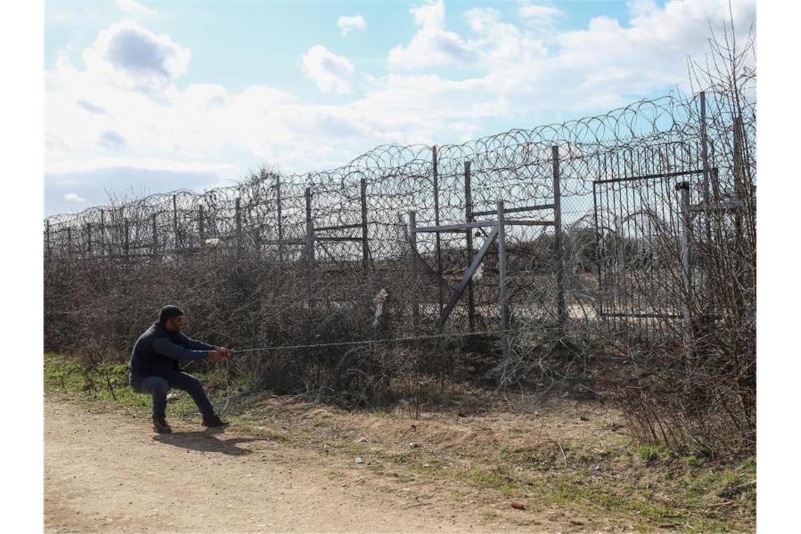 Ein Mann versucht, einen Teil des Grenzzauns einzureißen. Foto: Emrah Gurel/AP/dpa
