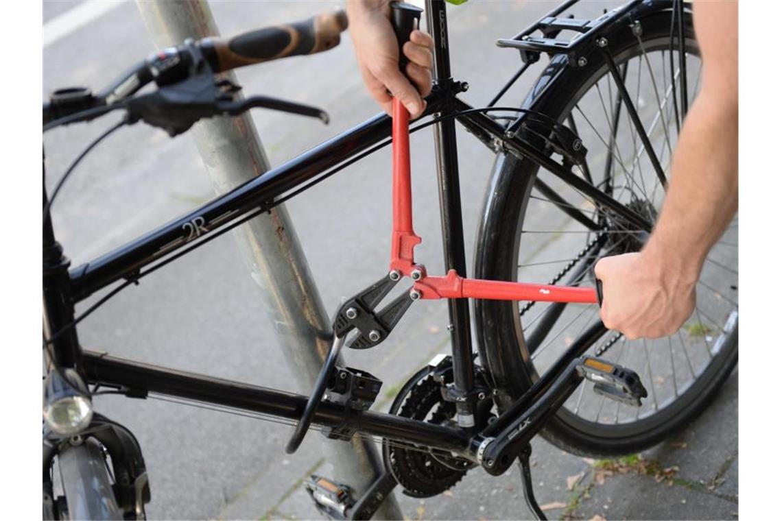 Ein Mann versucht mit einem Bolzenschneider ein Fahrradschloss aufzubrechen. Foto: Andreas Gebert/Archivbild