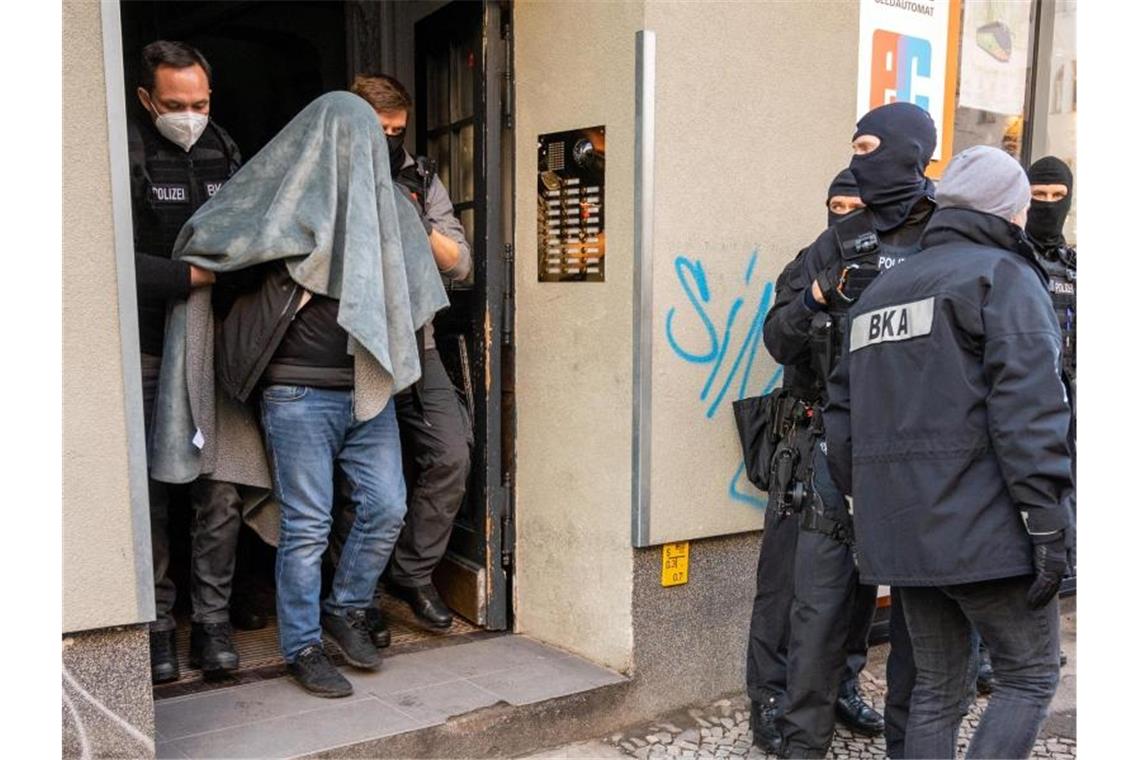 Kriminellen-Chats geknackt: Schlag gegen Clan-Kriminelle Ein Mann wird bei einer Razzia, mit einer Decke über dem Kopf, von der Polizei abgeführt. Foto: Christophe Gateau/dpa