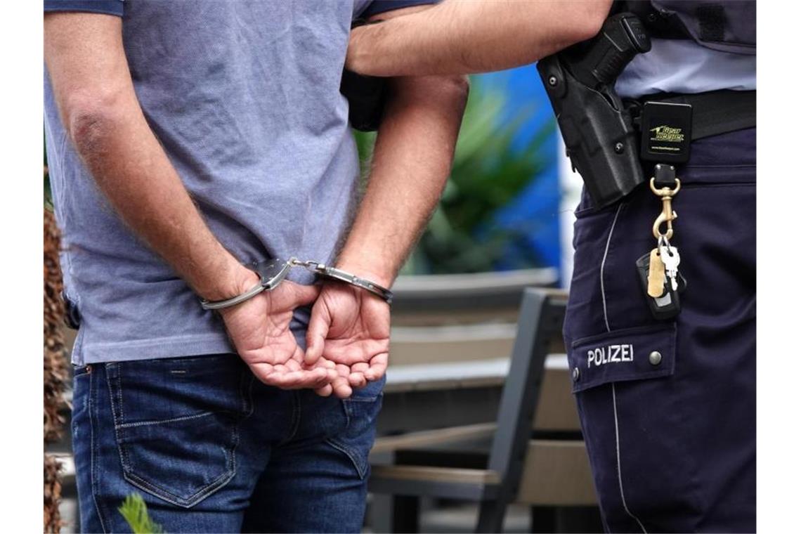 Autofahrer braust der Polizei davon und wird festgenommen Ein Mann wird in Handschellen abgeführt. Foto: Johannes Neudecker/dpa/Symbolbild