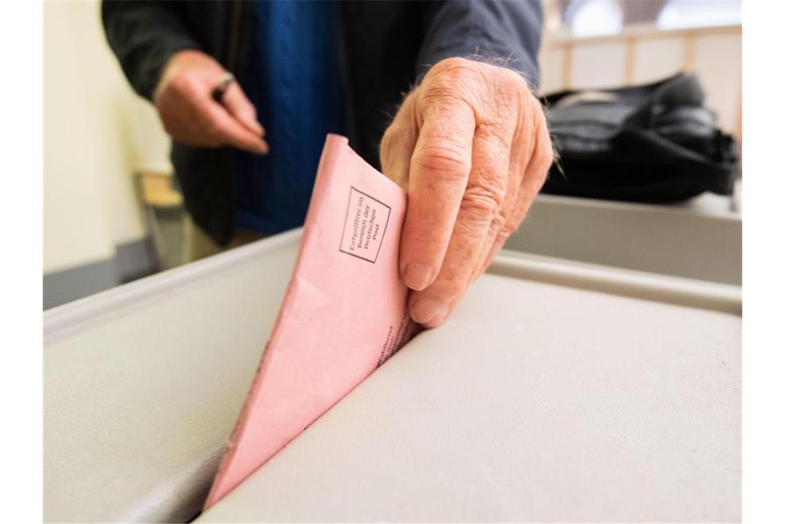 Ein Mann wirft seinen Stimmzettel in eine Wahlurne. Foto: Julian Stratenschulte/dpa/Symbolbild