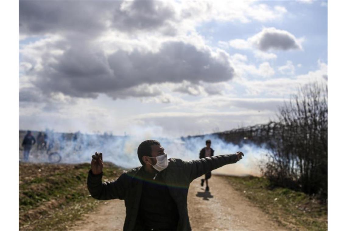 Ein Mann wirft von der türkischen Seite aus einen Stein. Foto: Emrah Gurel/AP/dpa