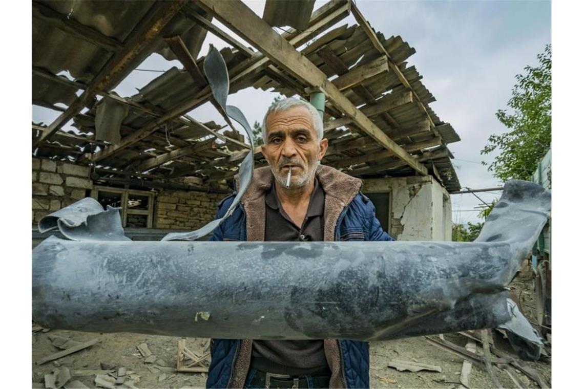 Ein Mann zeigt die Reste einer Rakete, die sein Haus im armenischen Martuni zerstört hat. Foto: Celestino Arce Lavin/ZUMA Wire/dpa